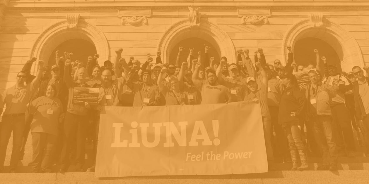 Group of Liuna members holding a sign with the Liuna logo with their fists in the air.