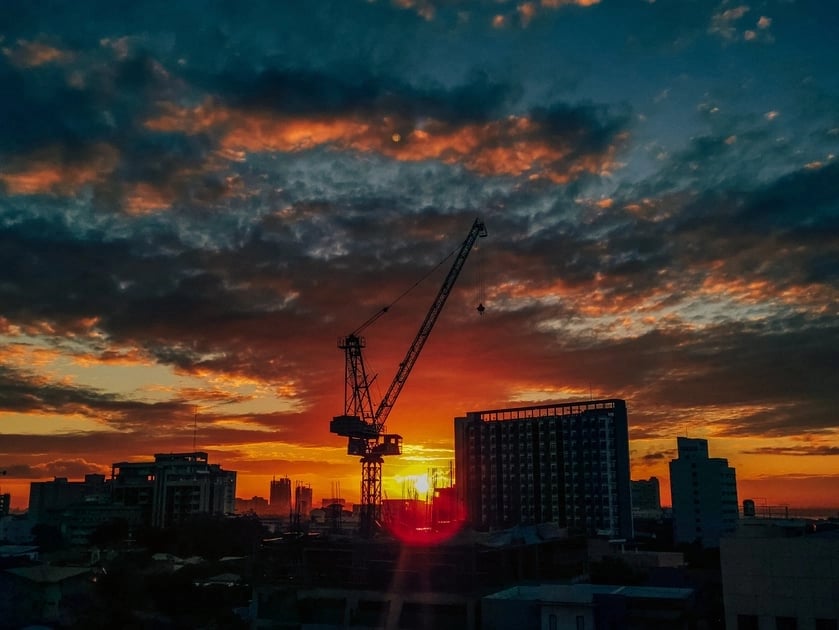 A crane in front of the sunset in a big city.
